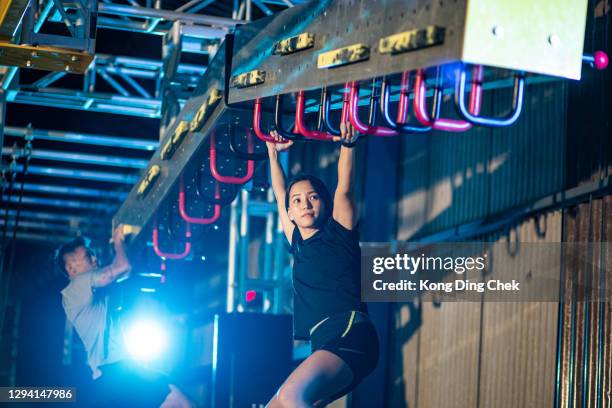 asiatische chinesische partner sportler training in einem hindernisparcours. incline monkey bar, cliff hanger - hindernisparcours stock-fotos und bilder
