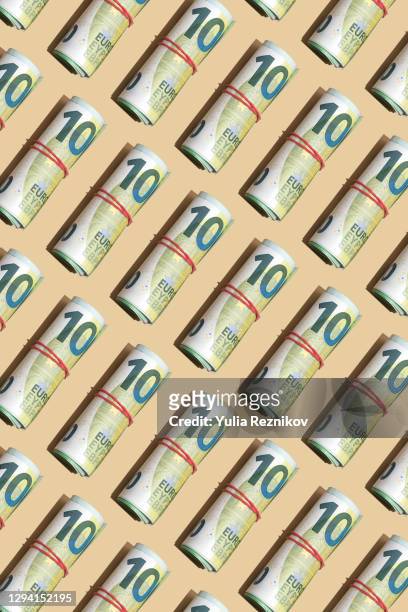 roll of 100 euro banknotes on the beige background - rolled up stockfoto's en -beelden