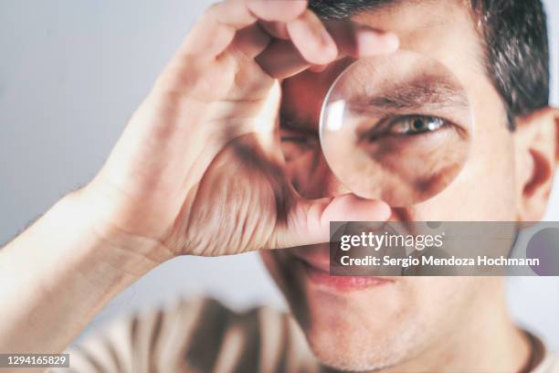 close up portrait of a man looking through a magnifying glass - squinting stock pictures, royalty-free photos & images