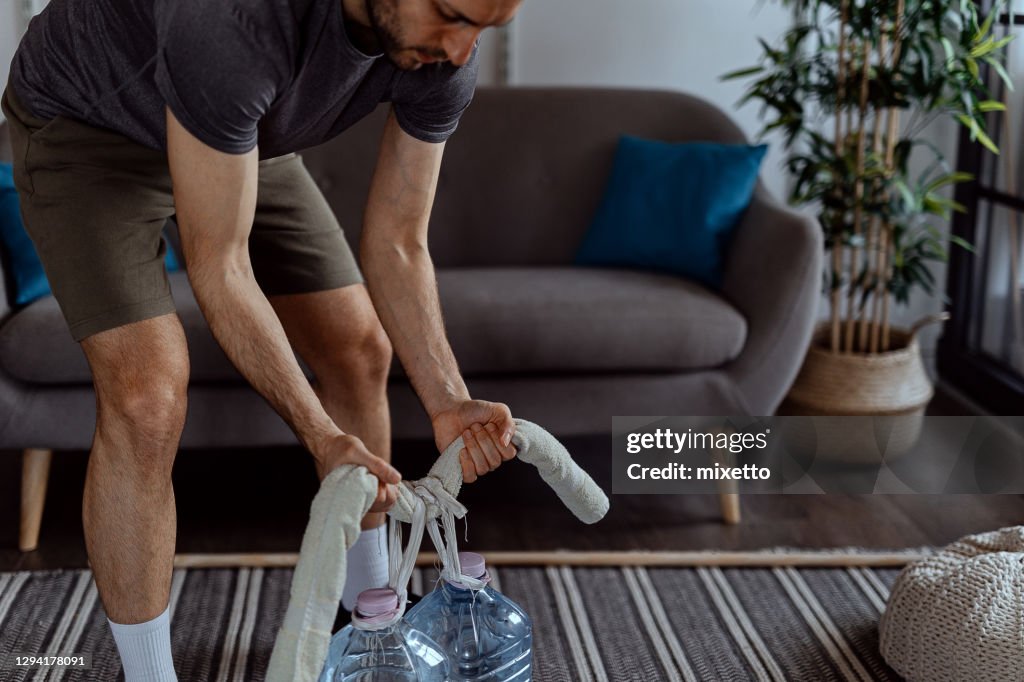 Young man exercising with a gallon of water at home