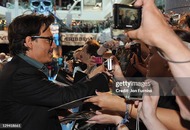 Actor Johnny Depp signs autographs for fans as he arrives for the UK Premiere of 'Pirates Of The Caribbean: On Stranger Tides' at Vue Westfield on...