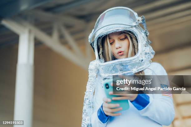 important call. young serious astronaut is holding a helmet and a modern mobile phone while looking at the device screen with concentration. isolated with copy space on the left side. - child in space suit stock pictures, royalty-free photos & images