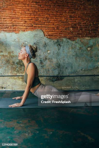 side view of a blonde woman doing yoga at home - cobra stretch stock pictures, royalty-free photos & images