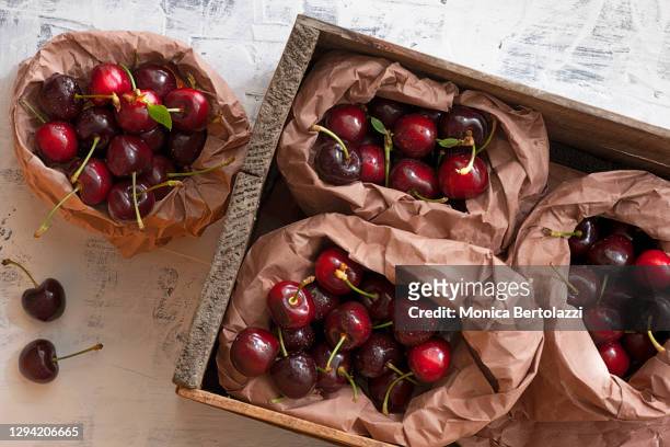 cherries in wooden box - bolsa de cor creme fotografías e imágenes de stock