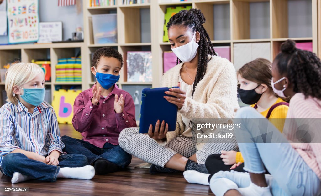 Professor de pré-escola, alunos em sala de aula, usando máscaras