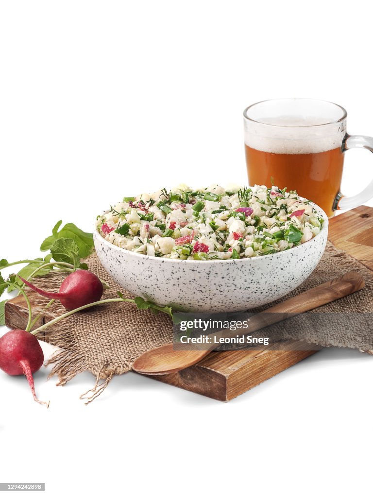 Food photography of okroshka, traditional Russian dish, a mixture of meat and vegetables with kvass, cold summer soup side view in a rustic style on a white background isolated close up. First course