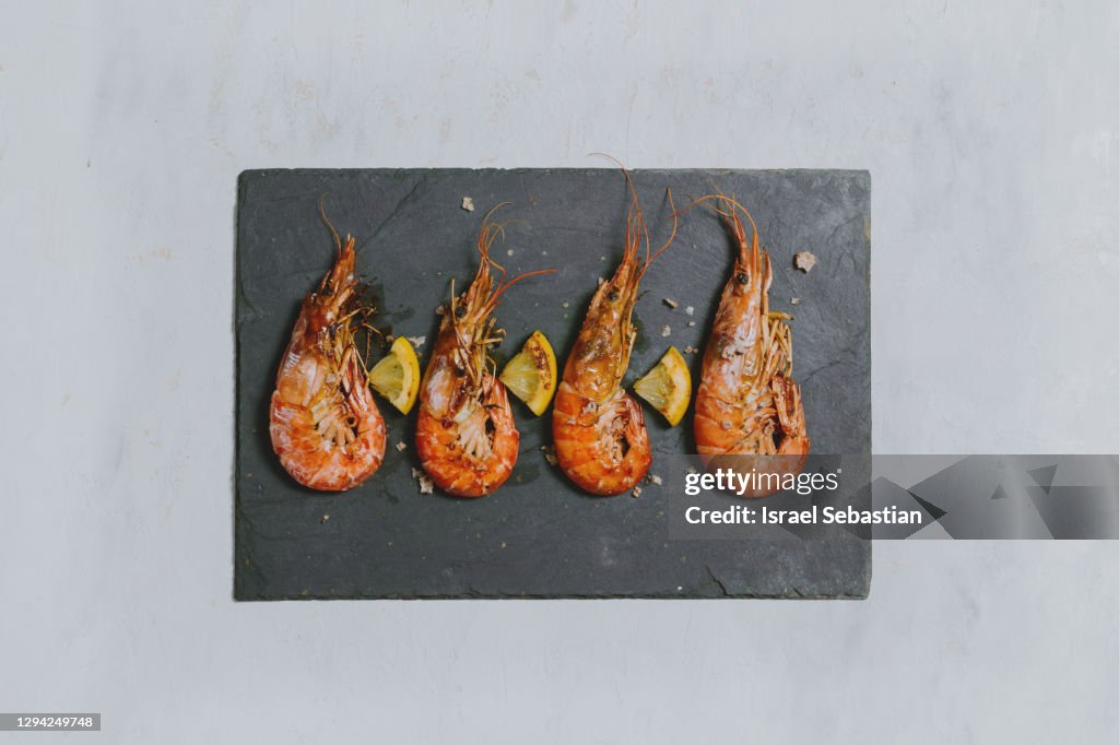 Roasted shrimp with salt on a black stone slab.