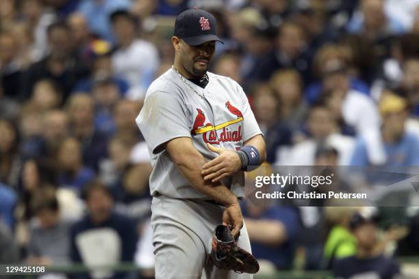 Albert Pujols of the St. Louis Cardinals grabs his right arm after he hurt it at a play at first base against Ryan Braun of the Milwaukee Brewers in...