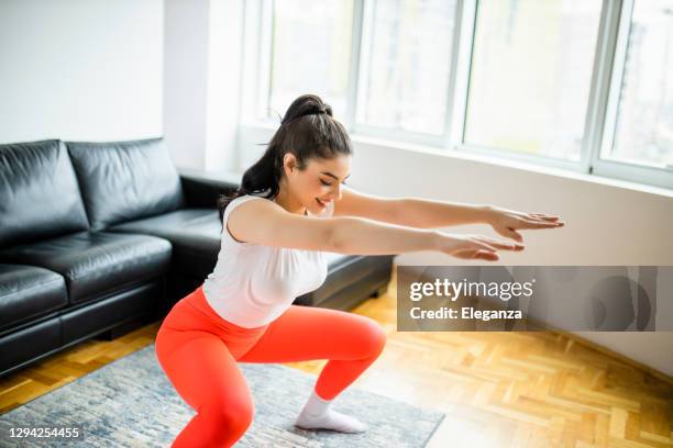 positive sportive woman in tight sportswear doing squatting  at home - rear end stock pictures, royalty-free photos & images