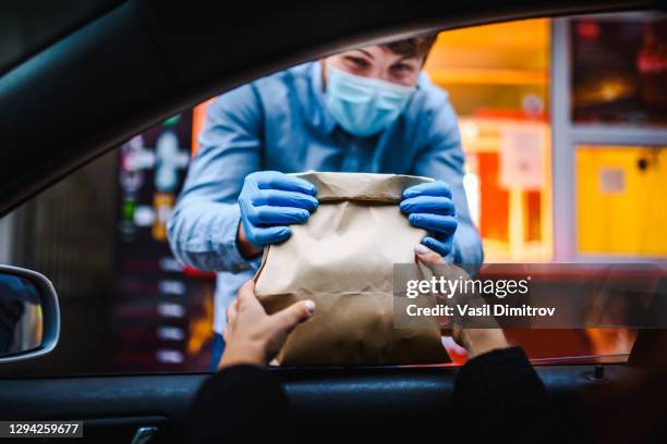 mulher pegando comida de restaurante de seu carro em uma foto de estoque curva pick up.  pegue o serviço de alimentos e bebidas durante a pandemia covid. - driving mask - fotografias e filmes do acervo