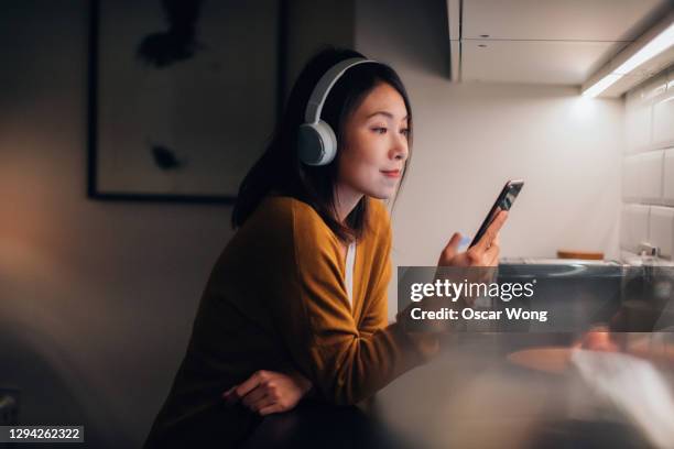 young woman with bluetooth headphones listening to music on smartphone - podcast 個照片及圖片檔