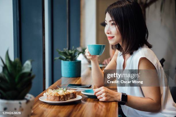 smiling young woman having breakfast at cafe - コーヒー　日本人 ストックフォトと画像