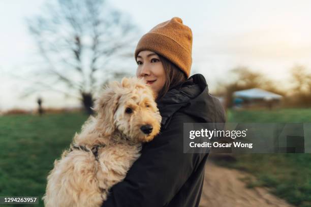 young woman embracing her dog at the park - mascota fotografías e imágenes de stock