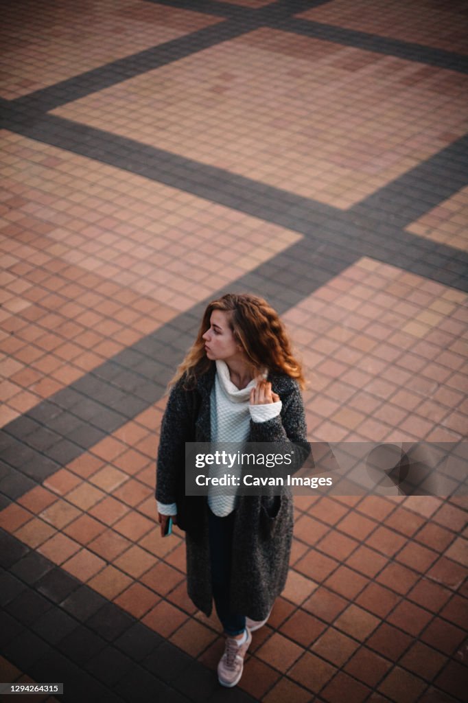 High angle view of teenage girl walking on city square in the evening