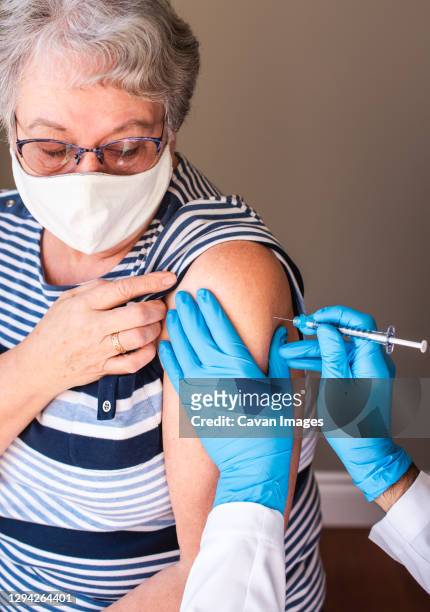 close up of older woman getting injected with a vaccine in upper arm. - gordelroos stockfoto's en -beelden
