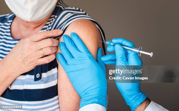 close up of older woman getting injected with a vaccine in upper arm. - herpes zoster stock pictures, royalty-free photos & images