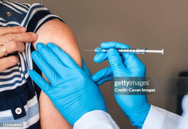 close up of woman getting injected with a vaccine in upper arm. - herpes zoster stock pictures, royalty-free photos & images