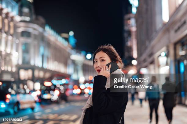 young woman talking on mobile phone on the city street at night - tourist talking on the phone stock pictures, royalty-free photos & images