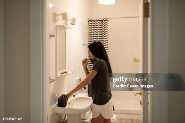 young female brushing teeth in bathroom - man washing his teeth stock-fotos und bilder