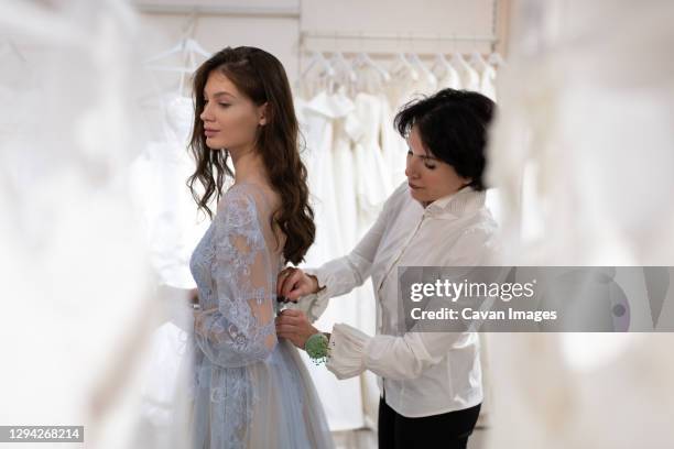 dress designer with female client trying on dress in atelier - bridal shop stockfoto's en -beelden