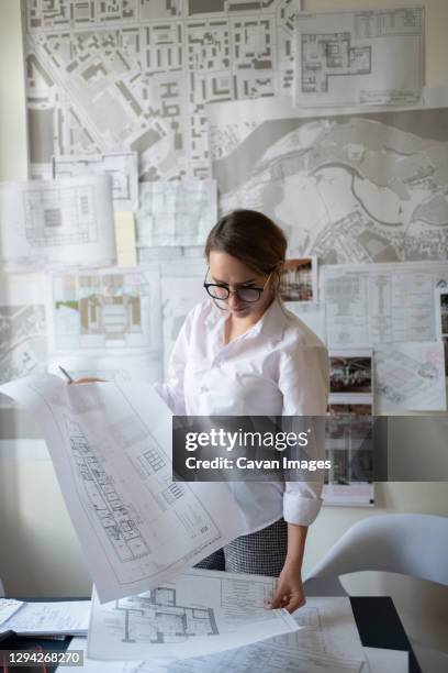 young female architect working with blueprints - womens draft ストックフォトと画像