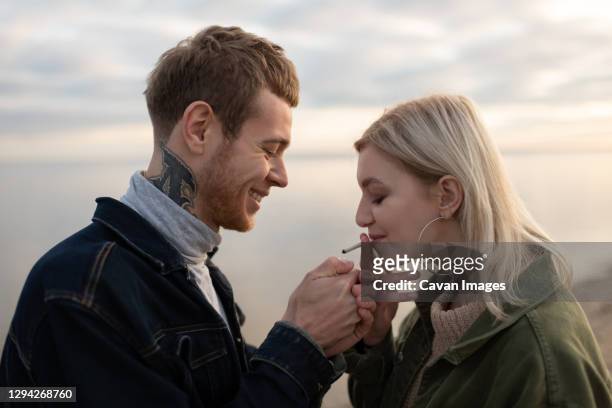 happy couple smoking weed in evening countryside - marijuana tattoo stock pictures, royalty-free photos & images