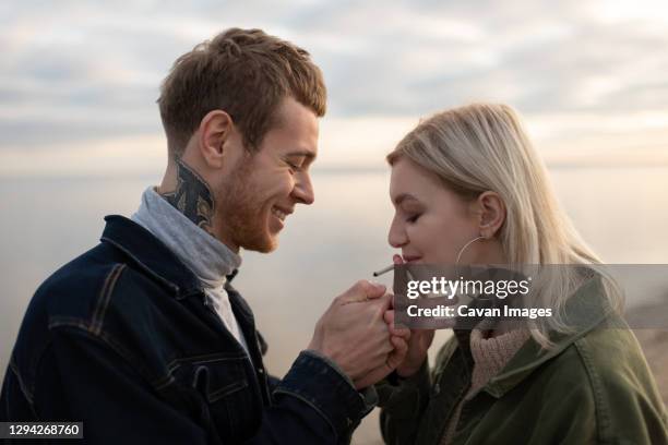 happy couple smoking weed in evening countryside - 大麻香煙 個照片及圖片檔