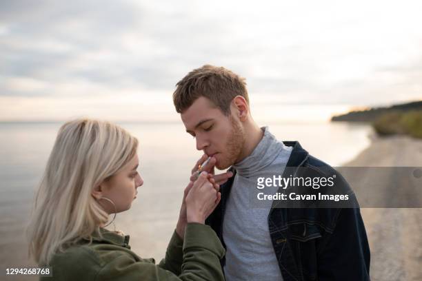 woman lighting cigarette for boyfriend - marijuana tattoo stock pictures, royalty-free photos & images