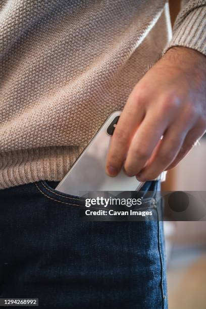 crop man taking out smartphone from pocket - hands in pockets stock-fotos und bilder