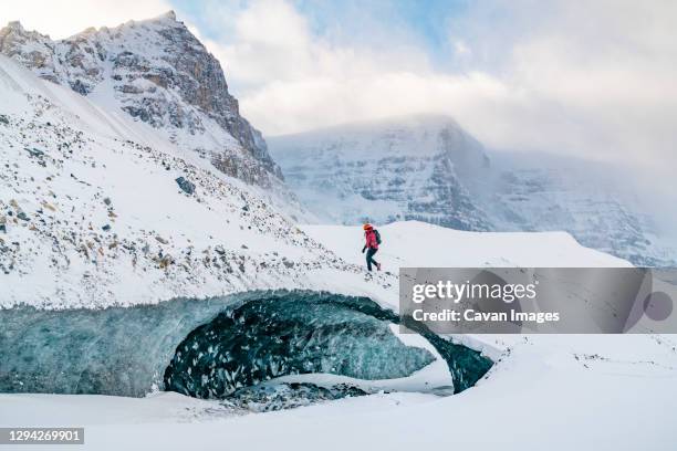 mountaineer climbs ice cave on icefields parkway - jasper canada stock pictures, royalty-free photos & images