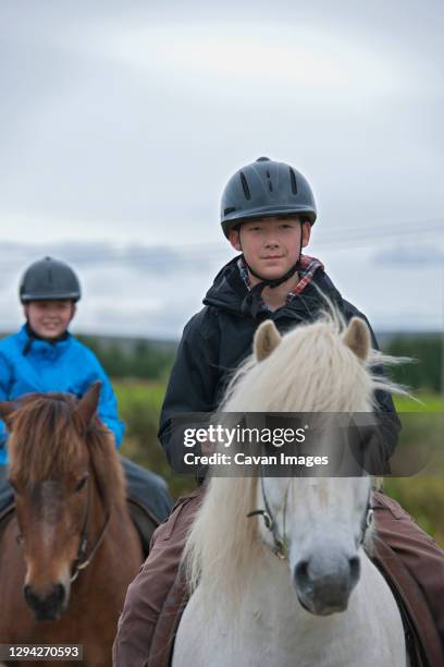 two brothers riding icelandic horses in remote location - iceland horse stock pictures, royalty-free photos & images