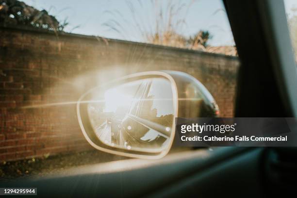 sun flare reflecting off a car's wing mirror - ignorancia fotografías e imágenes de stock