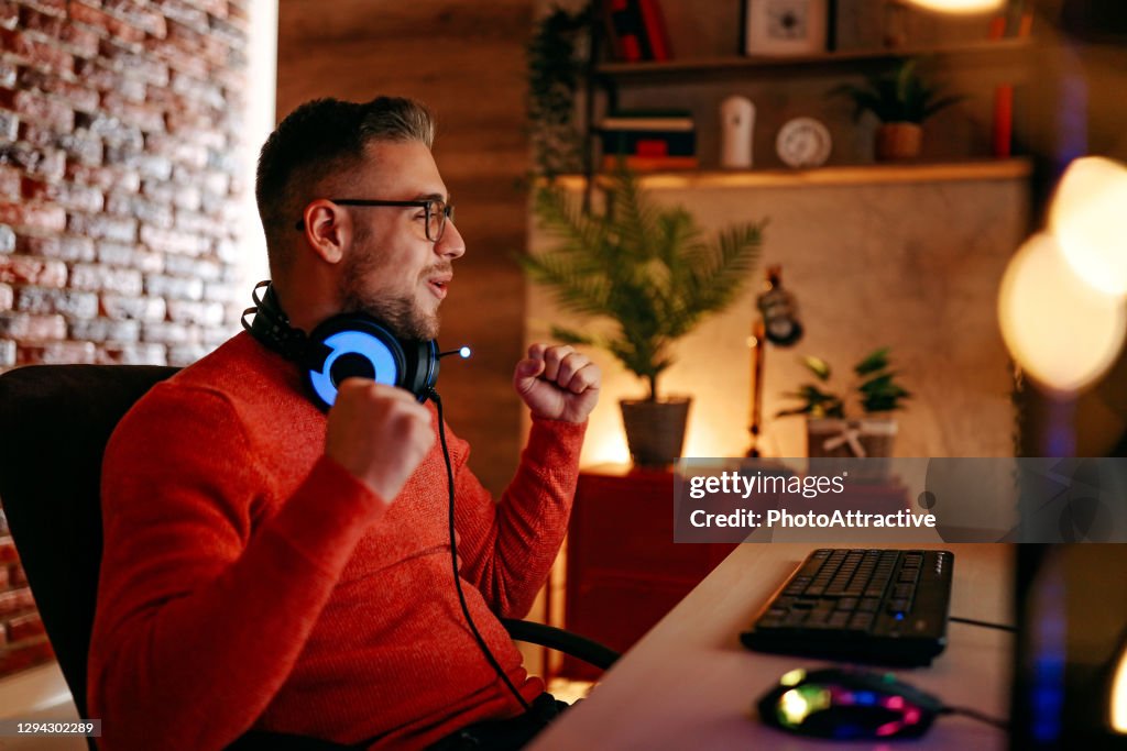 Mature man playing online games on laptop computer at home.