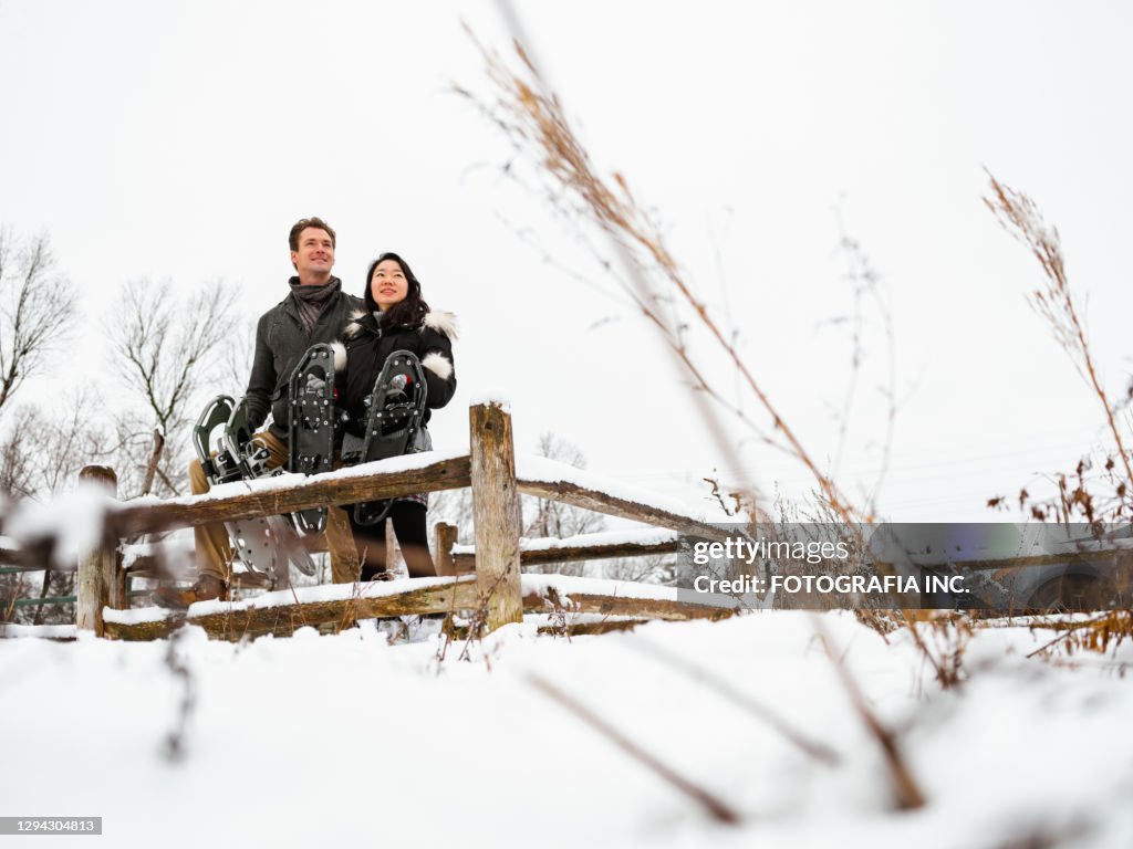 Mixed race couple snowshoeing in winter