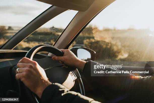 hand holding steering wheel in a car - rijden een motorvoertuig besturen stockfoto's en -beelden