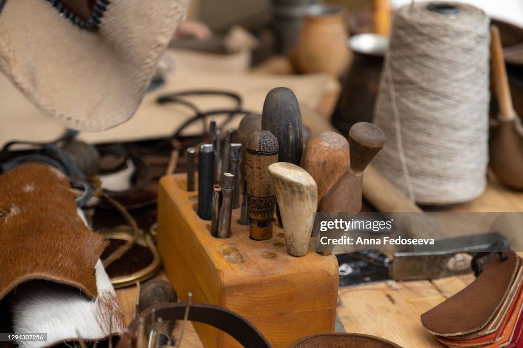 Workplace artisan. Tools for working with leather. Leather products. Wooden table.