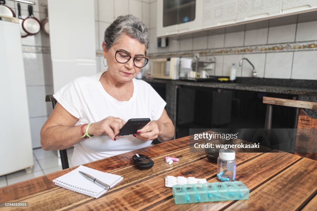 Senior woman recording her blood sugar level with a smartphone