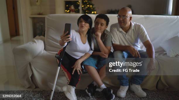 familie op laag die een videovraag op smartphone thuis doet - met inbegrip van een dwergmoeder - modern family media call stockfoto's en -beelden