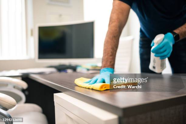 mann desinfiziert büroschreibtisch - hand sanitizer stock-fotos und bilder