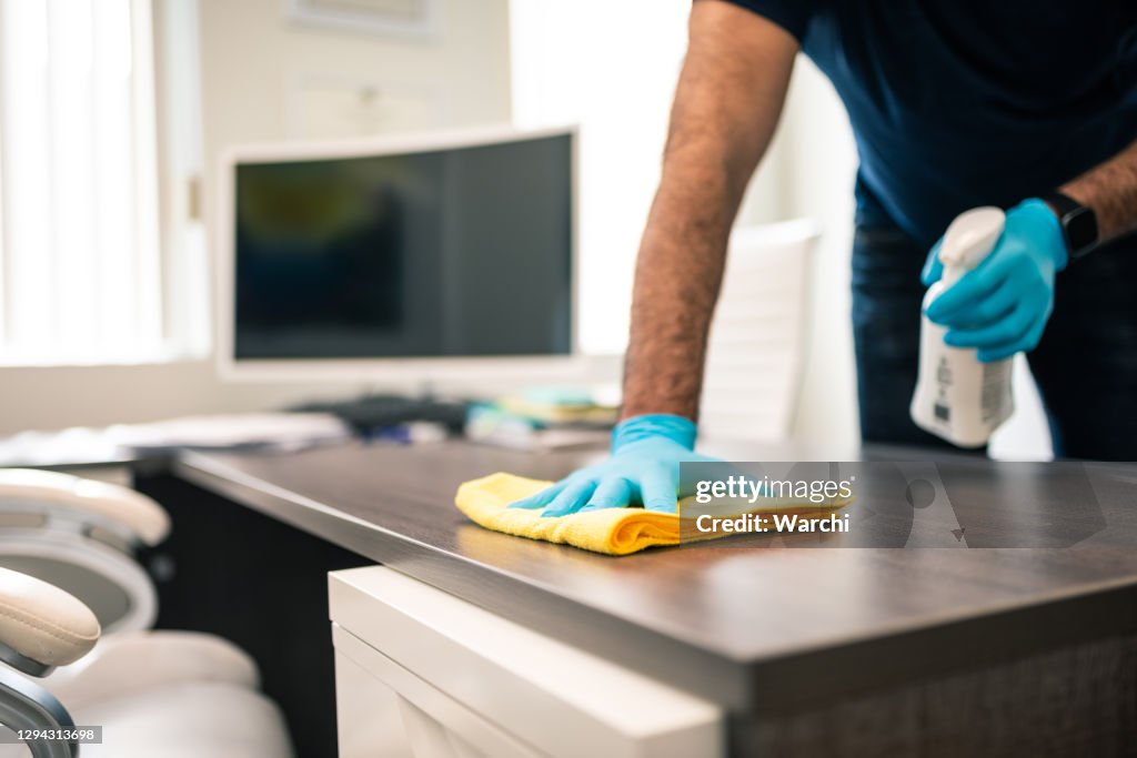 Hombre desinfectando un escritorio de oficina