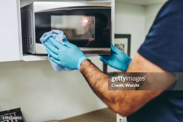 mains d’un concierge nettoyant le micro-ondes - microwave photos et images de collection