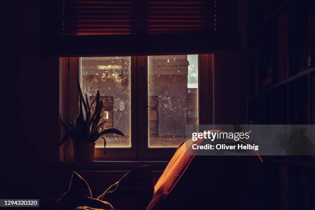 a living room with a red couch and dirty windows on a sunny afternoon - living room dark stock-fotos und bilder