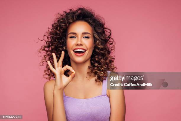 attraente giovane donna sorridente che mostra un segno ok - gesturing foto e immagini stock