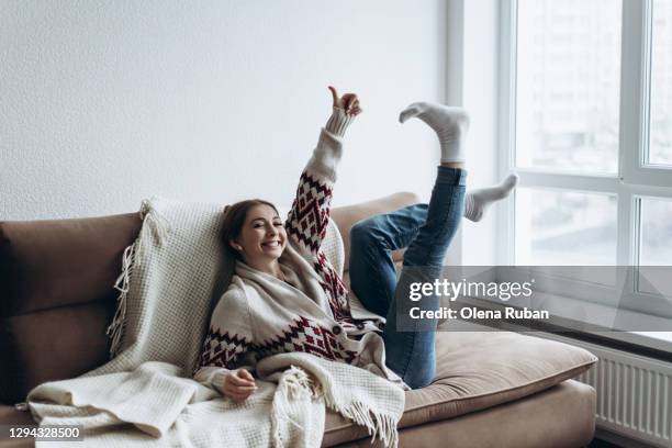 young woman in a sweater lies on the sofa by the window - charming stockfoto's en -beelden