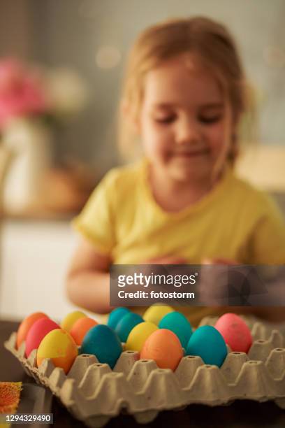 meisje dat paaseieren bekijkt zij verfde - carton of eggs stockfoto's en -beelden