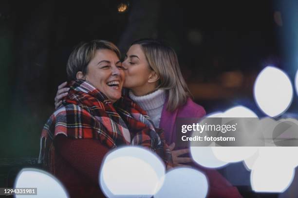 het geven van haar moeder een kus en het omhelzen van haar - mother and daughter on night street stockfoto's en -beelden