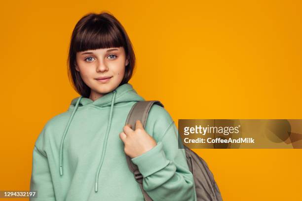 close-upportret van een jong mooi meisje in een groene hoodie met een rugzak - colourful studio shots stockfoto's en -beelden