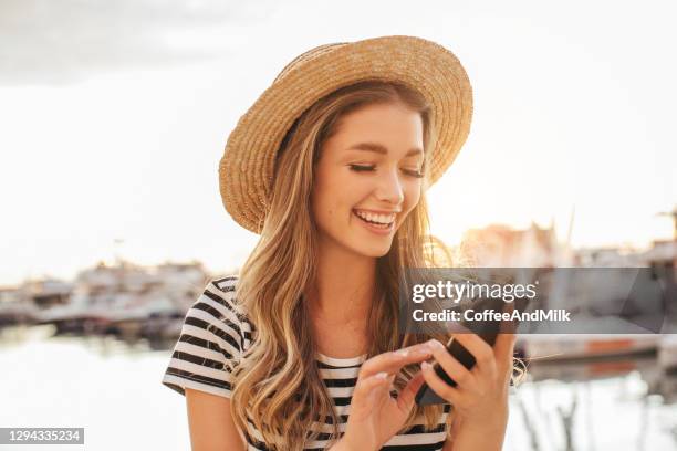 woman with smart phone near marina - one young woman only phone smiling stock pictures, royalty-free photos & images