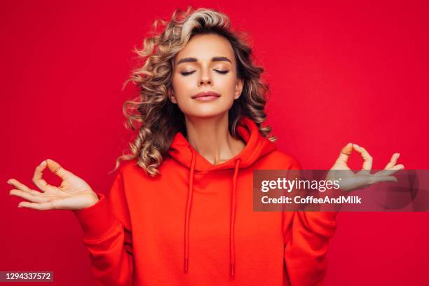 beautiful woman wearing red hoodie doing yoga - teen meditating stock pictures, royalty-free photos & images