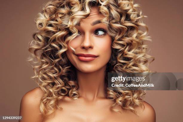 studioporträt von attraktiven jungen frau mit voluminöser lockigen frisur - haarpflege stock-fotos und bilder